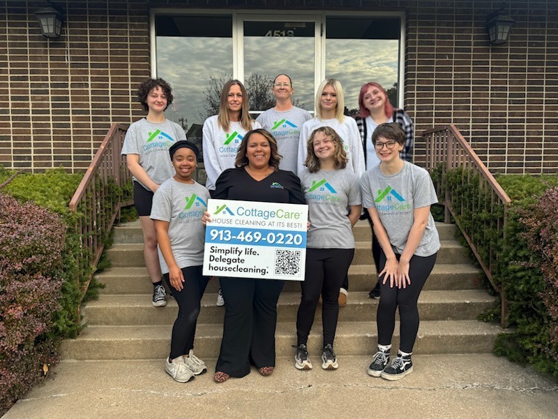 Group photo of CottageCare Prairie Village, Kansas Service Center Manager Cassandra Ross with her professional house cleaning crew outside their office holding a sign with their phone number (913) 341-1818.